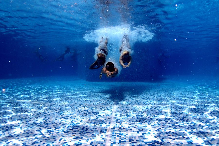 Fotograf&iacute;a de un grupo de deportistas sumergi&eacute;ndose en piscina durante el curso de nataci&oacute;n